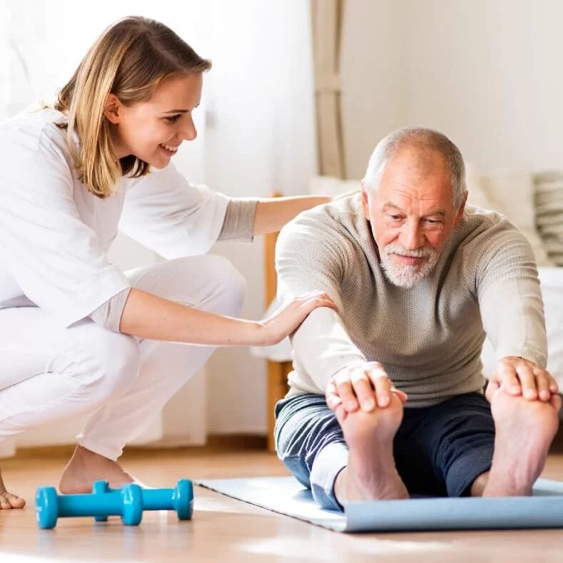 Fisioterapeuta mulher loira de jaleco orientando idoso na prática da fisioterapia em seu domicilio home care